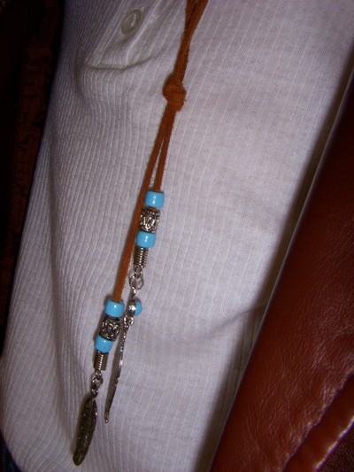 halsband med blå/turkosa pärlor och metallgrjesfjädrar.