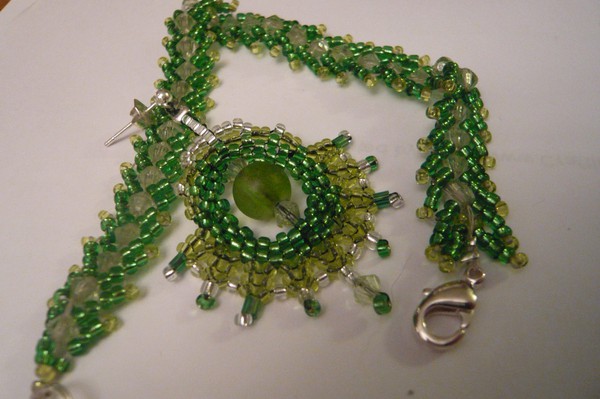 Grönt örhänge.  Swarovskikristaller och de flesta seed beads är Miyuki.  Örhängena är sydda med peyote-, och herringbonestygn.  Armbandet är sytt med St.Petersburgstygn.