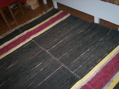 Denna matta är gjord av två likadana, som jag sytt ihop på mitten. För att de svarta partierna inte skall bli så kompakta har jag satt in röda trasor lite här och där.