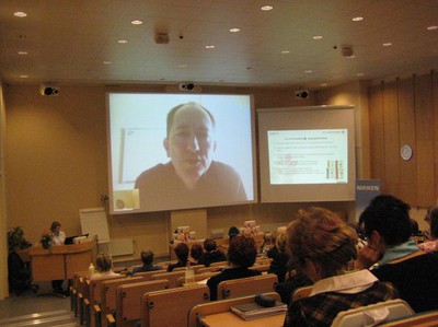 Mike Clenshaw på skärm i Tampere, via Skype.